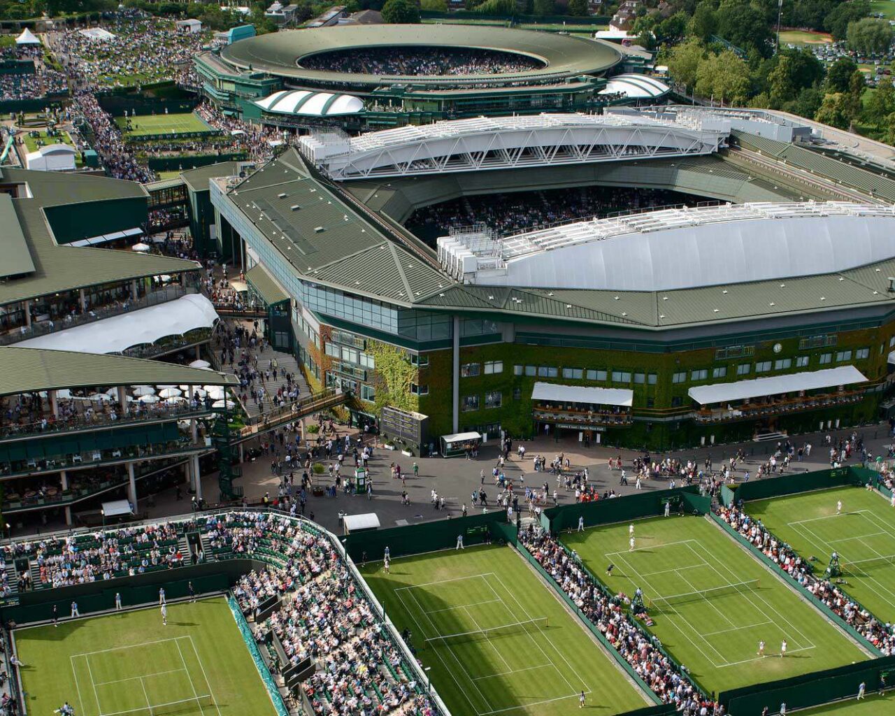Aerial view of the Wimbledon Tennis Championships venue, showcasing multiple courts and spectators.