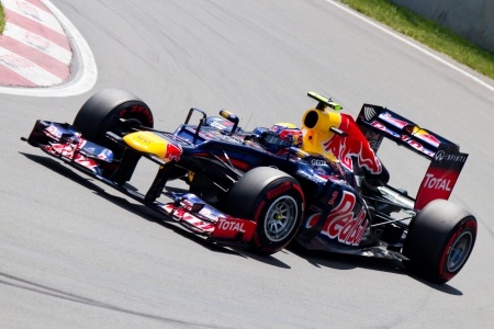A race car emblazoned with Red Bull and Total logos speeds along a track, capturing a dynamic moment in the Canadian Grand Prix history.