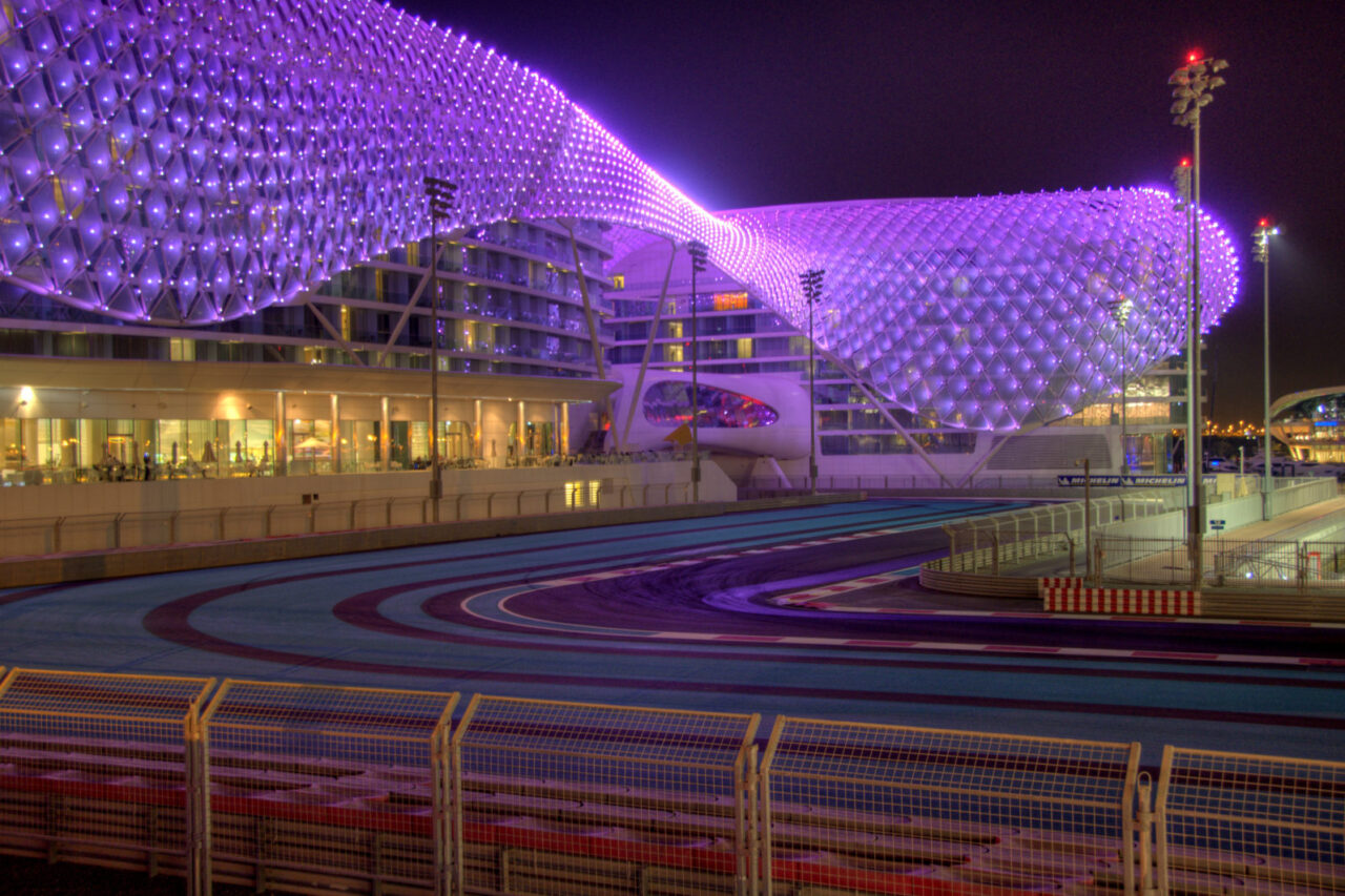 Yas Marina Circuit at night, highlighted by a glowing, geometric dome structure over a curving racetrack, renowned among F1's top grand prix circuits worldwide.