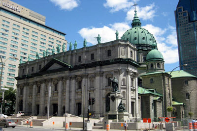A historical cathedral in Montreal, surrounded by modern buildings, suggested as a sight to see during the F1 Canadian Grand Prix events, capturing a blend of old and new architectural styles.