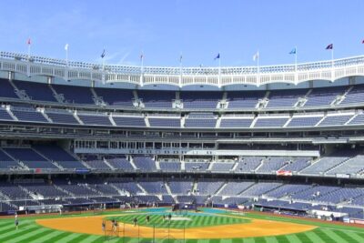 Empty baseball stadium with a detailed view of the field and stands under a clear blue sky, showcasing one of the greatest sights in New York for sports fans.