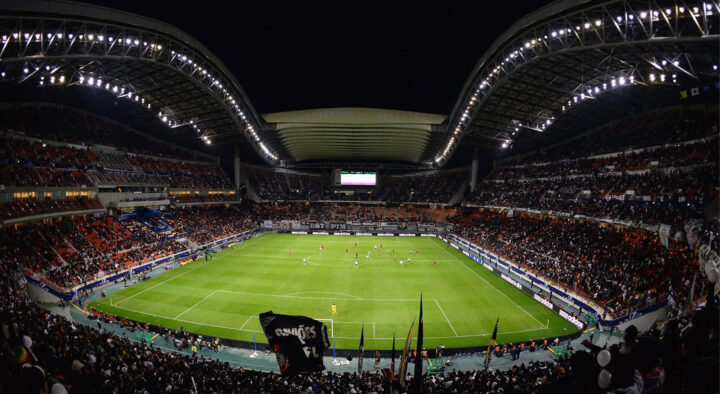 Nighttime soccer match underway at a large, illuminated stadium filled with spectators, suggesting one of the best group stage games at the World Cup.