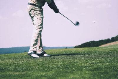 Golfer in mid-swing on a sunny day at the Masters Golf Tournament, demonstrating precision in a lush, green setting.