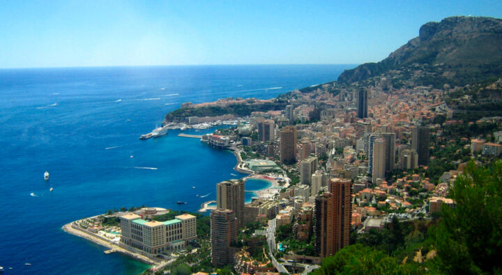 Spectacular aerial view of Monaco's coastline featuring dense urban areas and luxury sports travel experiences during the Grand Prix, highlighting popular restaurants and vibrant city life.