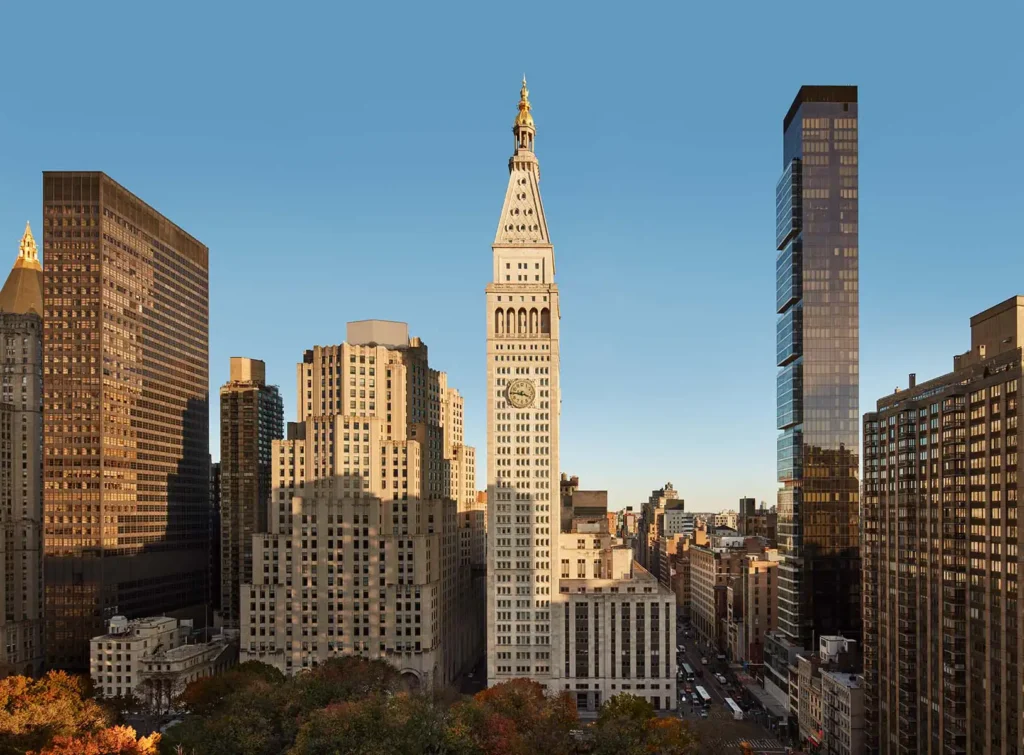 Aerial view of a bustling cityscape with a prominent clock tower surrounded by modern skyscrapers during fall, highlighting an urban setting relevant for luxury travel to major events.
