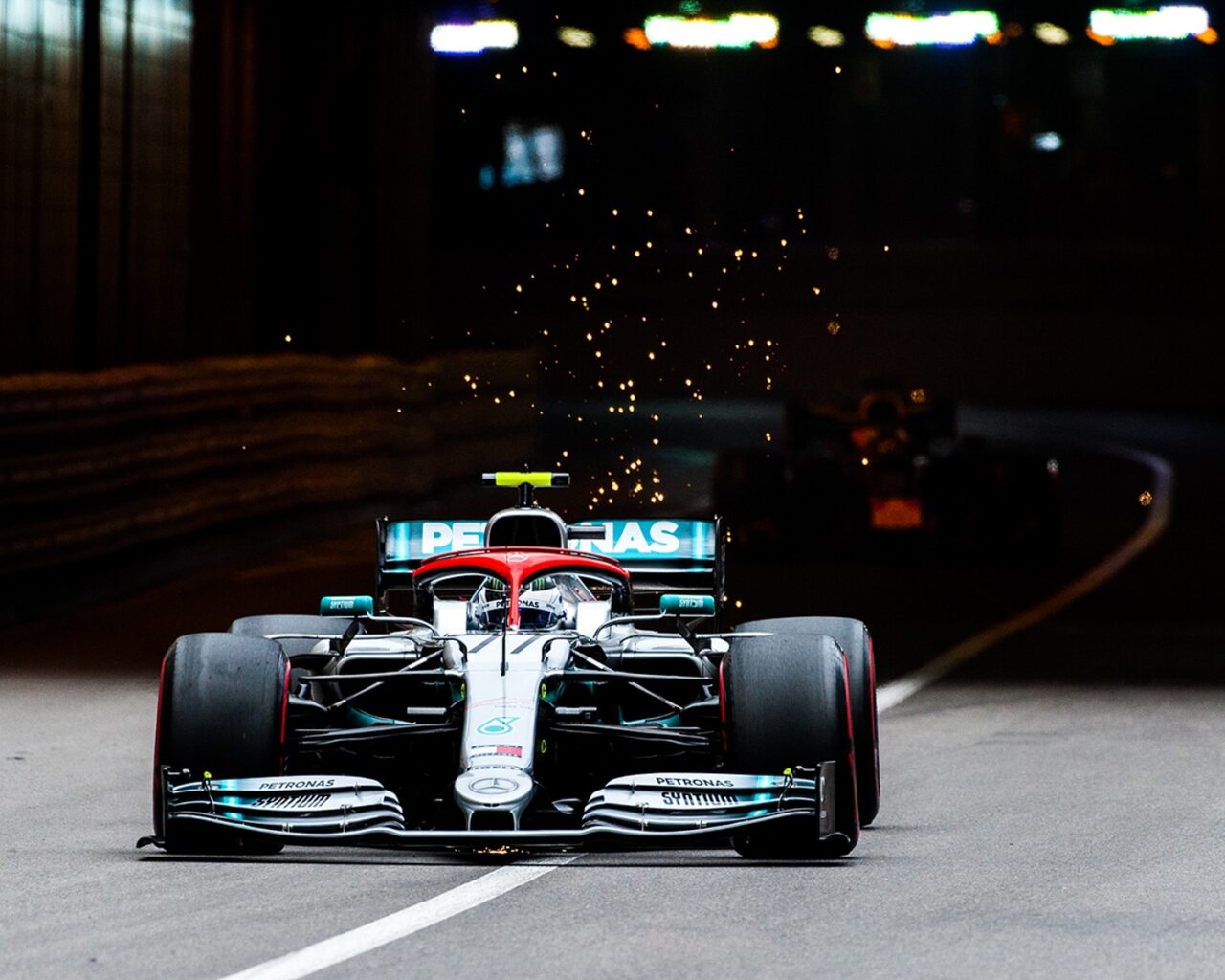 A Formula 1 race car speeds around a corner at night, sparks flying from the back, during a grand prix event, highlighting the excitement of US Grand Prix Packages.