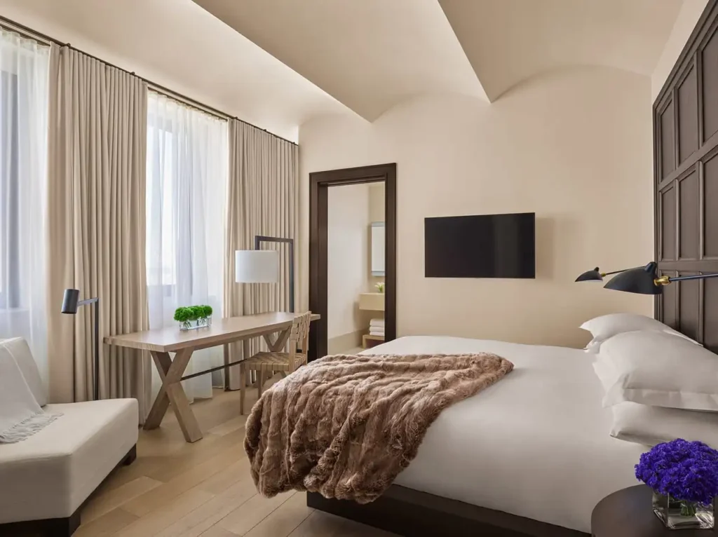 Luxurious guestroom at The New York EDITION, featuring a plush bed, desk area, and modern decor, ideal for Ryder Cup accommodations in New York.