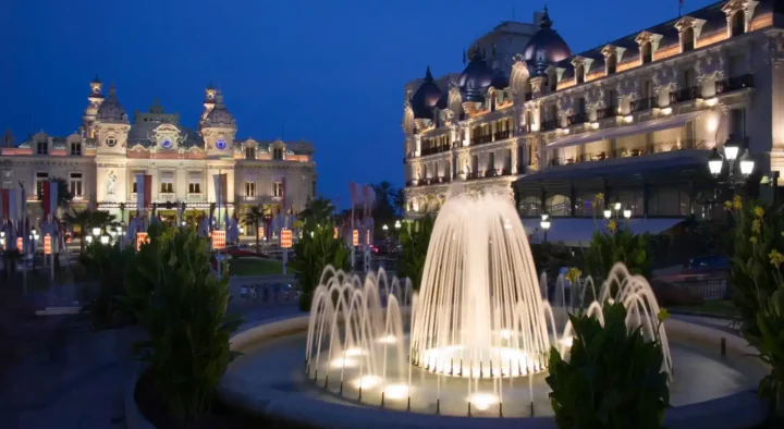 Illuminated fountain in front of Hotel de Paris in Monte Carlo, near locations for the Monaco Grand Prix, showcasing the vibrant nightlife and architecture of the area.
