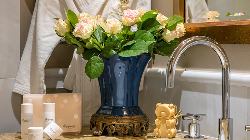 Luxurious bathroom setup at Hotel Hermitage in Monaco, showcasing a floral arrangement, upscale toiletries, and a decorative bear, ideal for Monte Carlo Hotels and Monaco Grand Prix hotel packages.