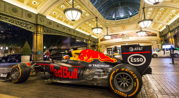 A Red Bull Formula 1 racing car displayed in a luxuriously decorated Las Vegas venue, promoting the Las Vegas Grand Prix schedule.