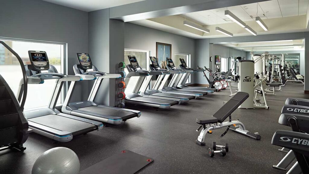 Modern fitness center in the Omni Louisville Hotel showcasing treadmills, weight machines, and cycling equipment, a convenient choice for guests attending events like the Kentucky Derby.