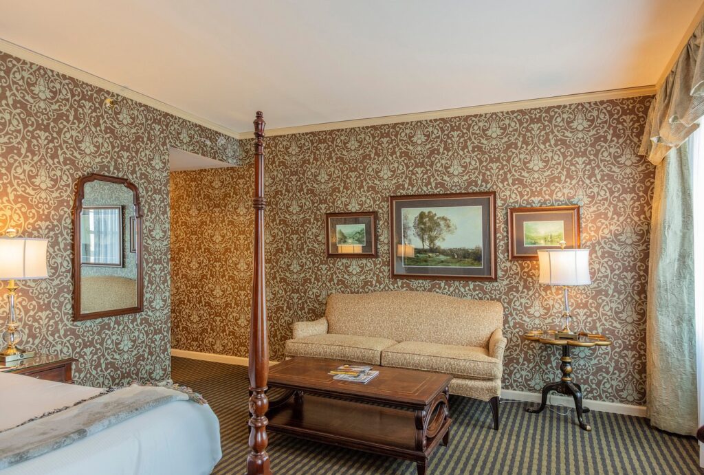 Elegant hotel room featuring ornate wallpaper, luxurious seating area, and classic furnishings, ideal for visitors looking for accommodations near Churchill Downs during the Kentucky Derby.