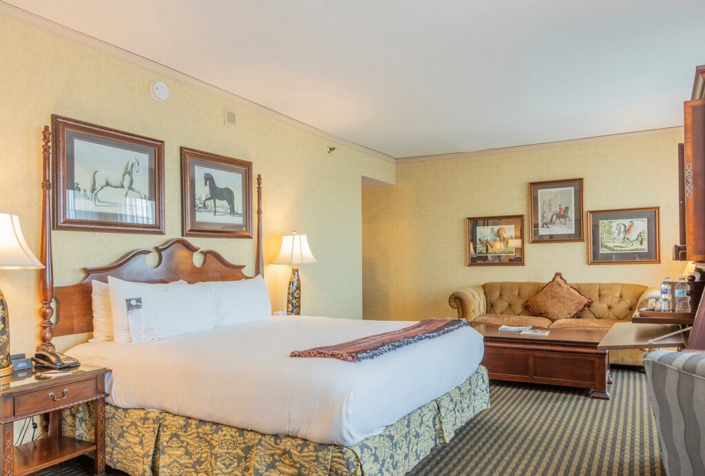 Elegant hotel room in Louisville, featuring a plush bed, classic furniture, and horse-themed artwork, ideal for guests attending the Kentucky Derby near Churchill Downs.