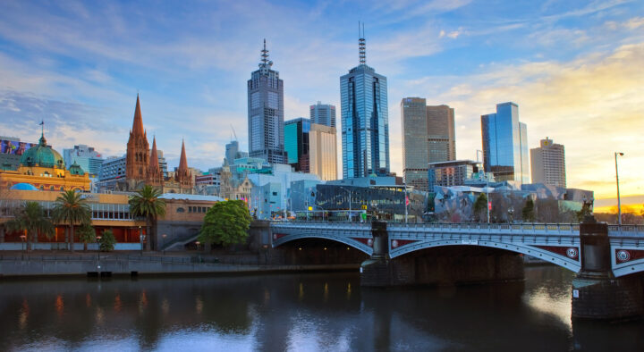 Sunset view of Melbourne featuring the Yarra River and iconic city architecture, including Melbourne Park in Australia, highlighted for the Australian Open.