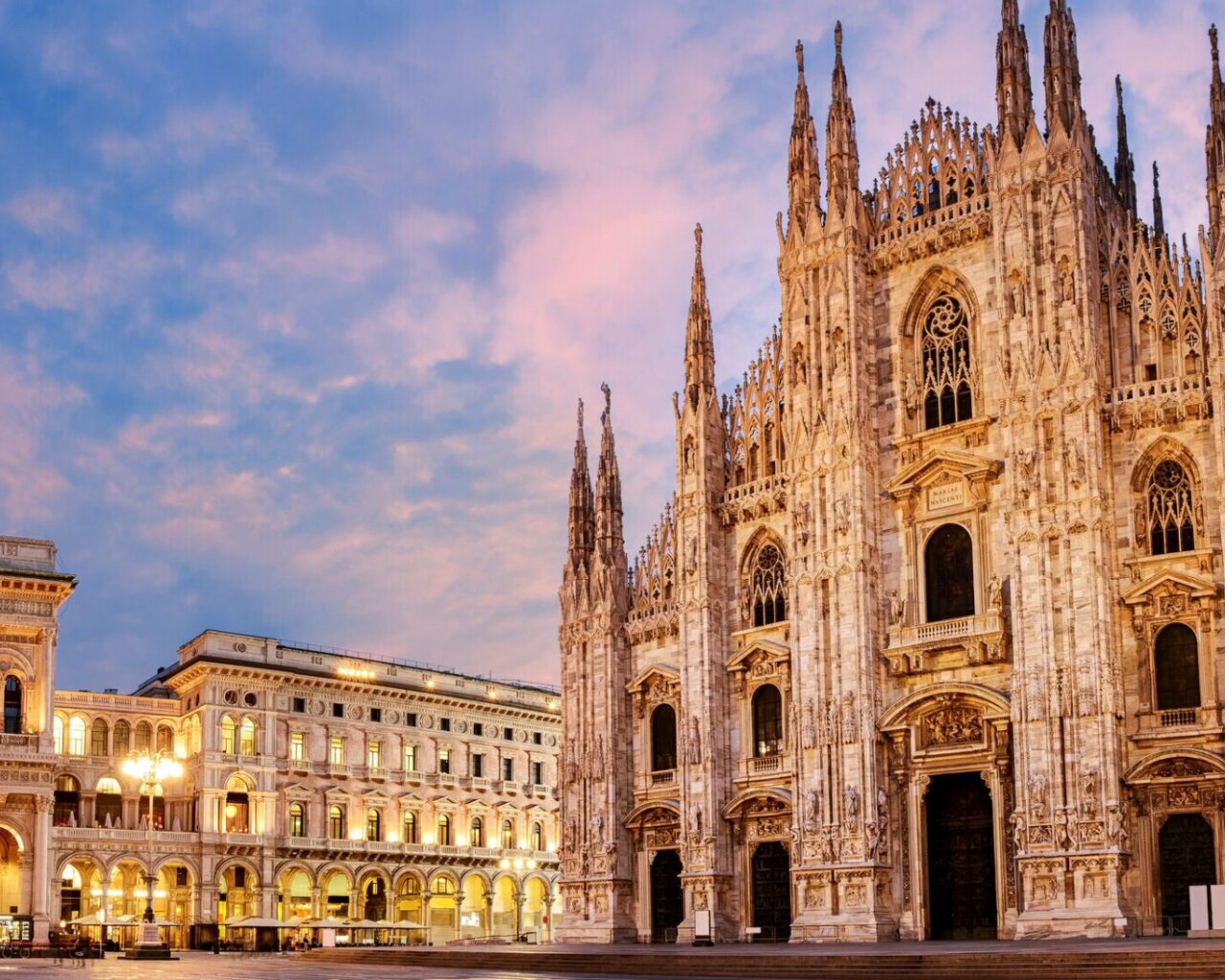 Milan Cathedral and Galleria Vittorio Emanuele II are illuminated at dusk, showcasing iconic architecture central to Winter Games events.