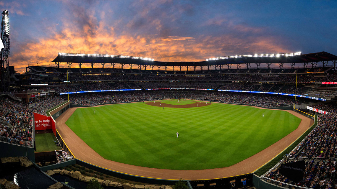 A panoramic view of a crowded baseball stadium during a game at sunset, showcasing vibrant skies and illuminated stands, perfect for luxury World Series travel packages.