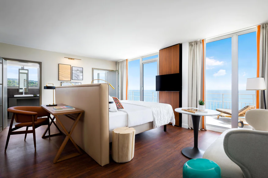 Spacious hotel suite at Le Meridien Nice featuring a modern decor with ocean views through floor-to-ceiling windows, ideal for Monaco Grand Prix enthusiasts seeking luxurious Monte Carlo accommodations.