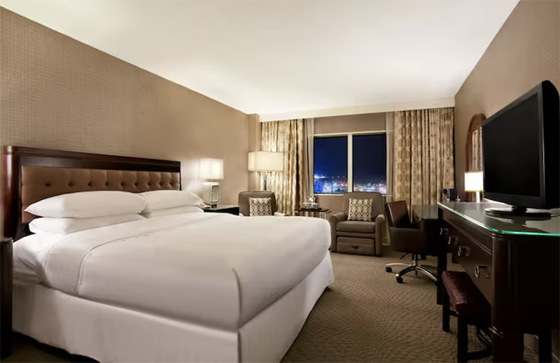 Luxurious hotel room at The Park Hotel at Meadowlands features a large bed, elegant furnishings, and a city view, ideal for travelers visiting New York for World Cup events.