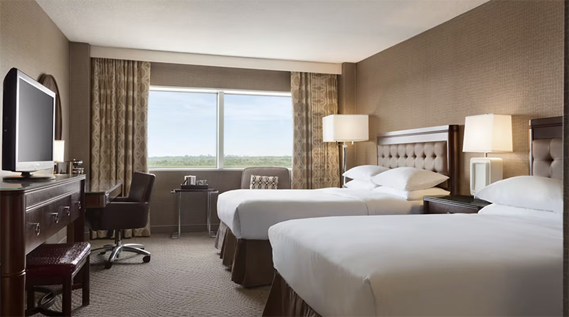 Interior view of a well-furnished hotel room at The Park Hotel, featuring two beds, a desk, and a large window, perfect for World Cup accommodations in the New York area.
