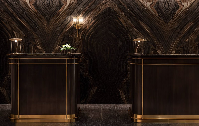 Elegant interior of The Ritz-Carlton, South Beach featuring two stylish reception desks against a striking marbled wall, an ideal accommodation choice for attendees of the Club World Cup in Miami.