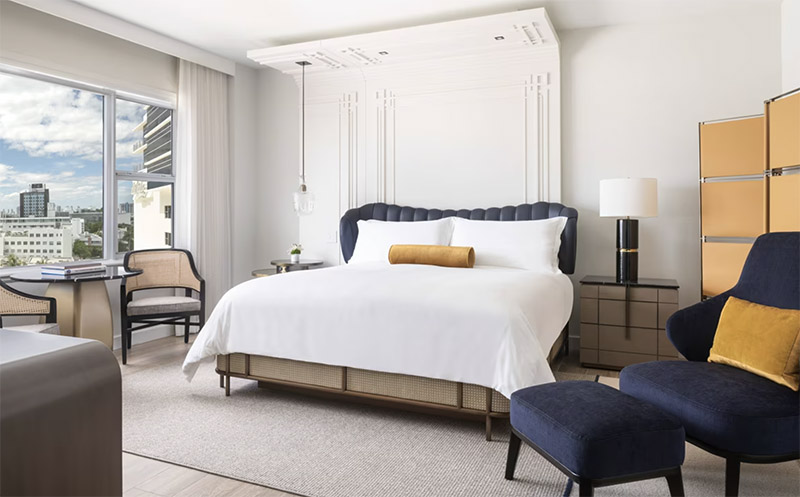 Luxurious hotel room at The Ritz-Carlton, South Beach featuring a large bed, stylish seating, and a view of Miami Beach, ideal for Club World Cup accommodations.