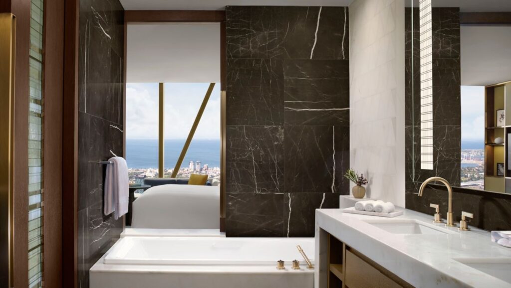 View from a luxurious bathroom with large windows displaying Melbourne's skyline, situated at The Ritz-Carlton Melbourne on 650 Lonsdale Street, a prime location for visitors to Melbourne Park events.