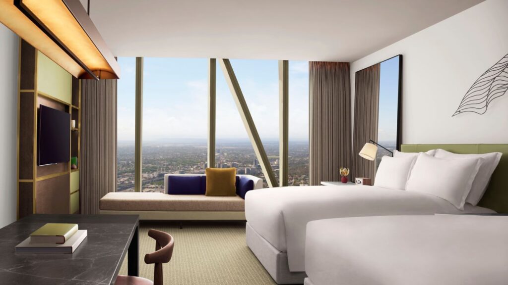 A luxurious hotel room at The Ritz-Carlton Melbourne, featuring a large window with a panoramic view of the city, ideal for guests visiting during the Australian Open at Melbourne Park.