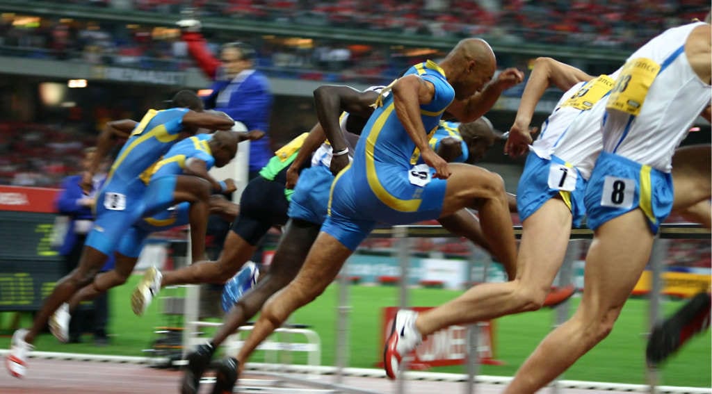 Male athletes in a tense sprinting race at a packed stadium, embodying the peak moments featured in luxury travel guides for top sporting events like the Champions League Final and the Indy 500.