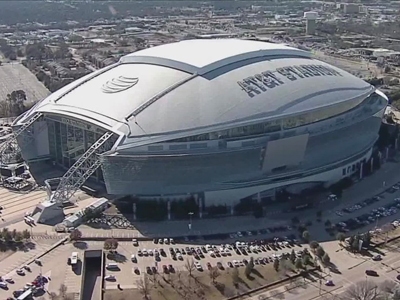 Aerial view of AT&T Stadium in Dallas, set to host the World Cup Semi-Final, showcasing its distinctive architecture and full parking areas.