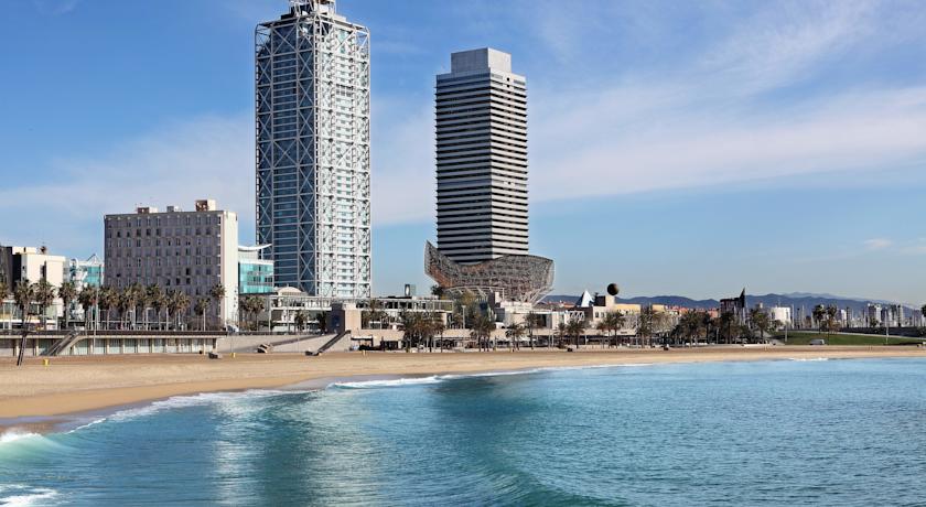 Luxury hotels on the beachfront in Barcelona, Spain, with clear blue waters and modern skyscrapers in the background, promoting accommodations for the Spanish Grand Prix.