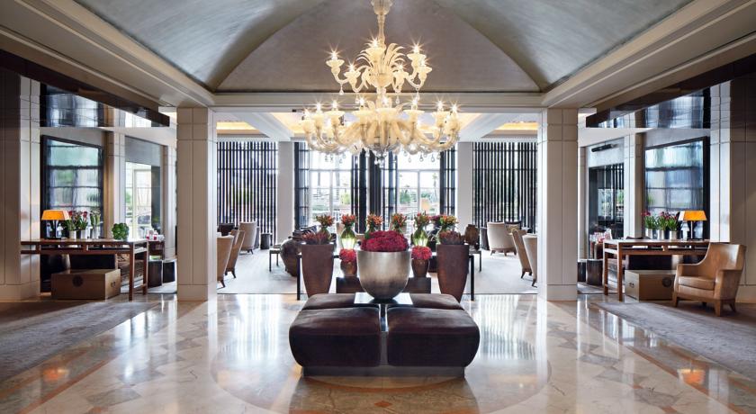 Luxurious hotel lobby in Barcelona featuring elegant seating, a grand chandelier, and vibrant floral arrangements, ideal for Spanish Grand Prix accommodations.
