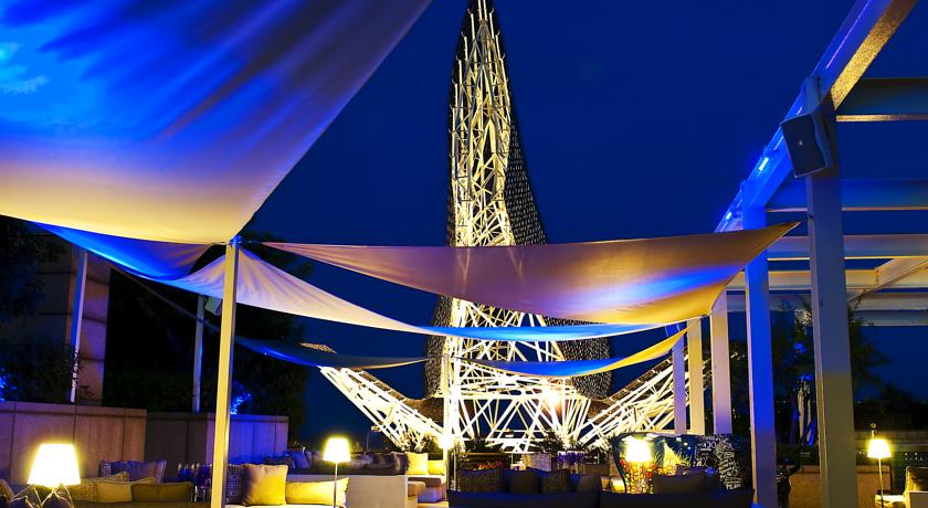 Night view of Hotel Arts Marina Barcelona, featuring an illuminated modern sculpture and luxury outdoor seating, ideal for guests attending the Spanish Grand Prix.