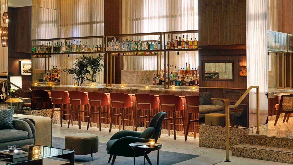 Elegant bar area inside the Thompson Hollywood by Hyatt in Los Angeles, featuring a lit-up bar counter, wooden paneling, and plush seating, ideal for Summer Games guests.