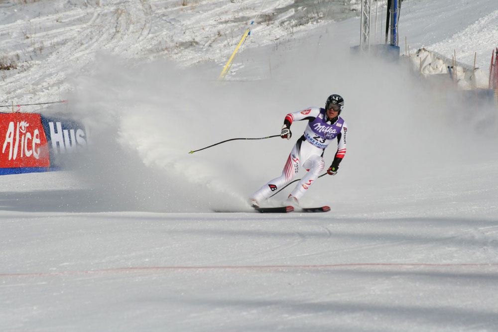 A skier competes in a downhill race, carving through snow with speed, showcasing athleticism at a winter sports event likely to appear in luxury travel guides for sports enthusiasts.