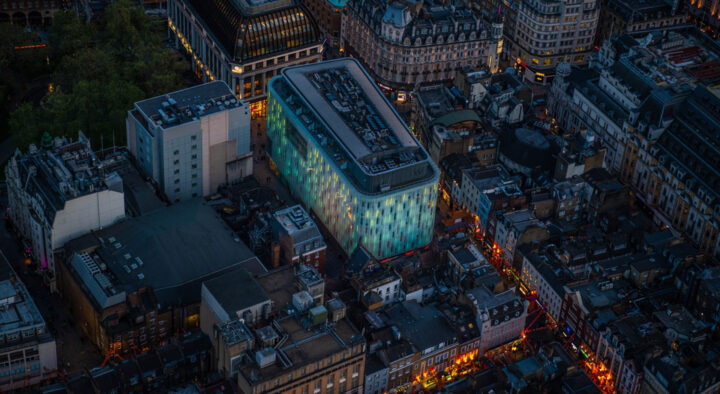 An aerial view of a brightly lit, modern hotel amidst classic architecture in Munich, highlighted for travelers seeking accommodations for the Champions League Final.