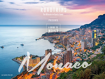 Luxury travel guide cover by Roadtrips featuring a scenic aerial view of Monaco at dusk, highlighting its dense cityscape and shoreline, aimed at upscale travelers interested in sports events.
