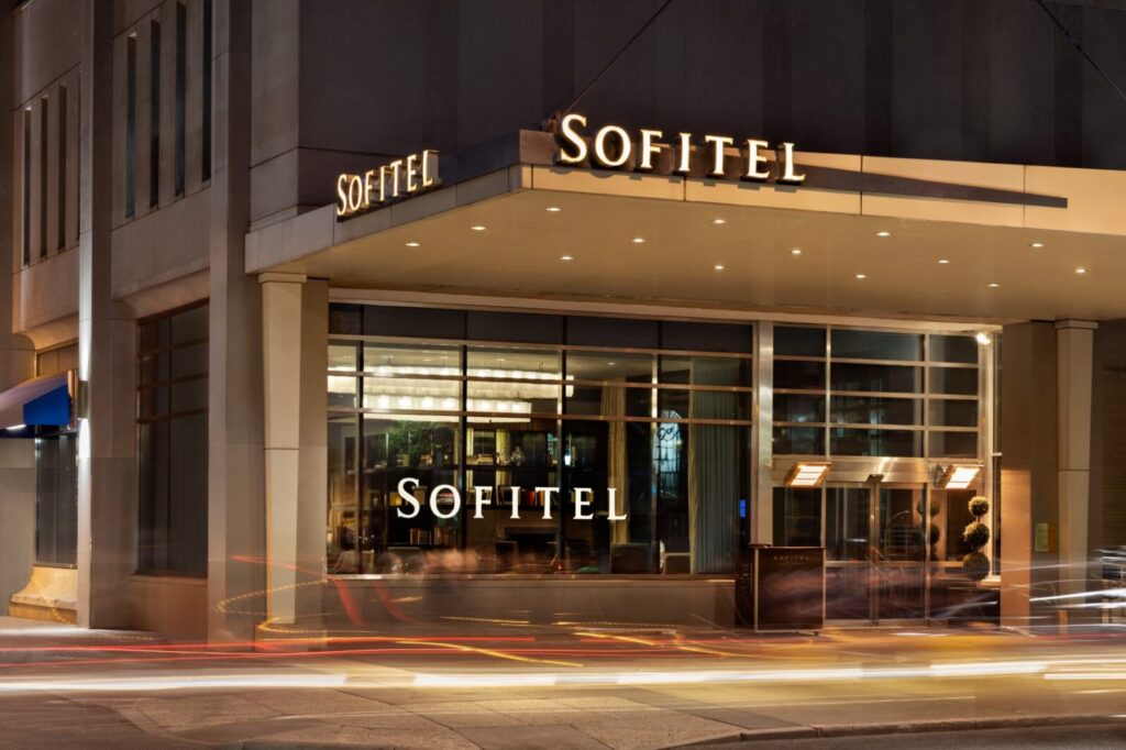 Nighttime view of Sofitel Philadelphia, featuring illuminated signage and bustling street traffic, located at Rittenhouse Square, a popular choice for World Cup Hotels & Accommodations in Philadelphia.