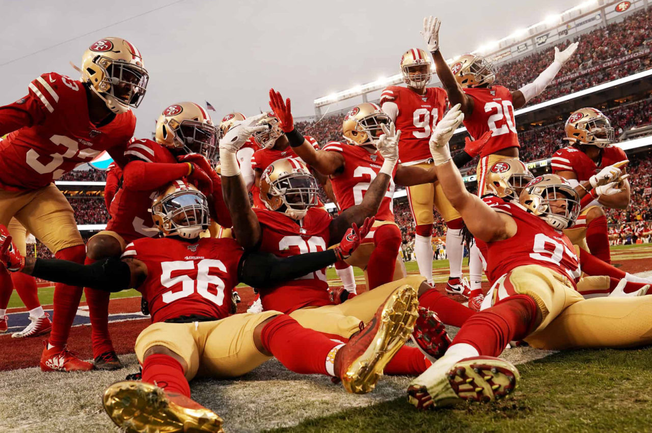 Several American football players in red uniforms celebrate enthusiastically on the field during a game, capturing the spirit of major sporting events like the Super Bowl.
