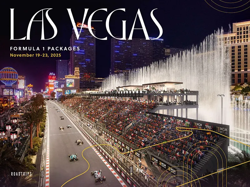 Nighttime view of Formula 1 cars racing down the Las Vegas Strip with large crowds and illuminated hotels during the Las Vegas Grand Prix, highlighting Roadtrips' luxury travel packages.